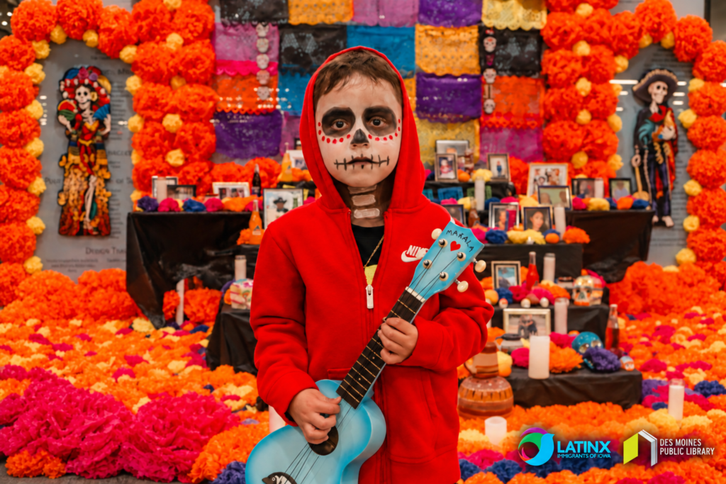 Niño frente a la ofrenda del Día de los Muertos organizada por Latinx Immigrants of Iowa en colaboración con la Biblioteca Pública de Des Moines